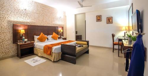 a hotel room with a bed and a table and a desk at Rosewood Apartment Hotel Pantnagar in Rudrapur
