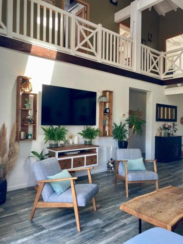 - un salon avec deux chaises et une télévision à écran plat dans l'établissement La Kasa Poza, à Biaudos