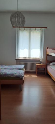 a room with two beds and a large window at Casa con giardino in centro in Pianezzo