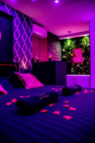 Cette chambre violette comprend un lit avec un éclairage rose. dans l'établissement Le secret des déoux love room, à Forcalqueiret