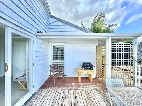 a white house with a deck with a table and a grill at Studio 35 Kerikeri in Kerikeri