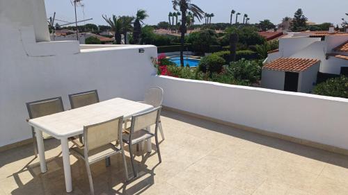 a table and chairs on the balcony of a house at Chalet calan Bosch Menorca in Cala'n Bosch