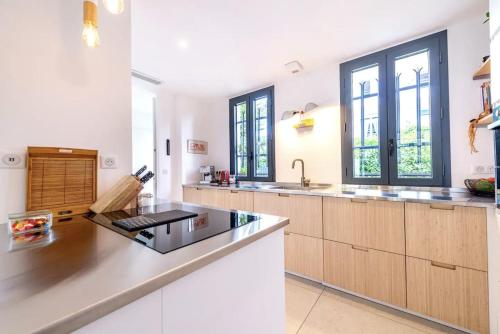 une grande cuisine avec des murs blancs et des placards en bois dans l'établissement Magical Villa with Secluded Garden - Beach, Port & Centre, à Vallauris