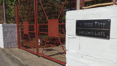 a gate with a sign on the side of a building at Anissa Tiny Garden Loft in Anissaras