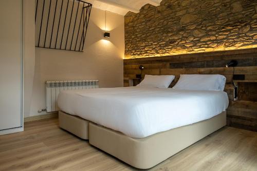 a large white bed in a room with a stone wall at Cal Marrufès in Puigcerdà