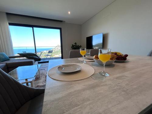 a dining room table with two glasses of orange juice at Saraiva Hills Ocean View Penthouse in Câmara de Lobos
