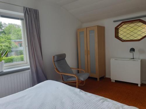 ein Schlafzimmer mit einem Bett und einem Stuhl und einem Fenster in der Unterkunft Cozy apt in 50s villa 10 min tram ride to city in Göteborg