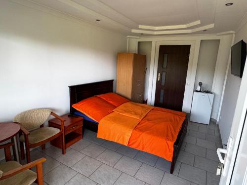 a bedroom with a bed with an orange blanket at POMERANIA Pokoje U Oliwii in Rewal