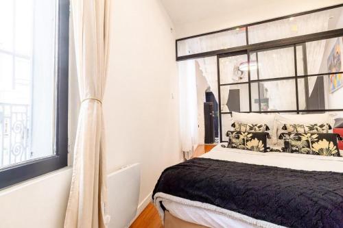 un dormitorio con una cama y una ventana en Le 2e Colombier, en Colombes