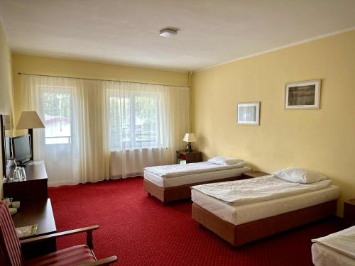 a hotel room with two beds and a television at Hotel Mazury in Giżycko