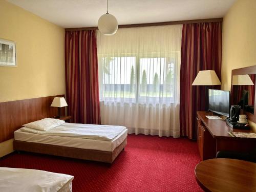 a hotel room with two beds and a desk and a television at Hotel Mazury in Giżycko