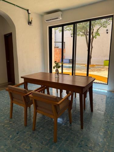 a wooden table and bench with a table and a window at Casa Bernarda in Mérida