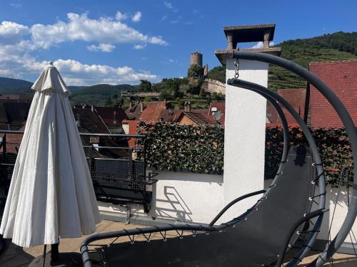 a chair and an umbrella on a balcony at Le Rooftop du Schlossberg in Kaysersberg