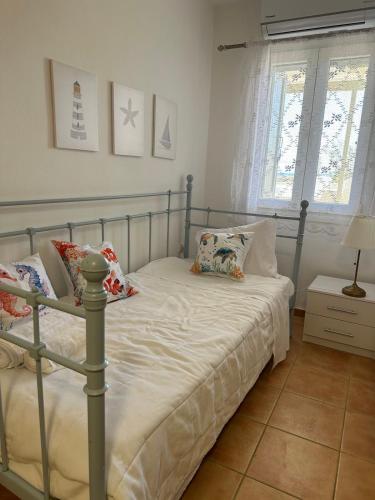 a bedroom with a bed with white sheets and pillows at Tinos dream sea ,150m from the beach in Agios Sostis