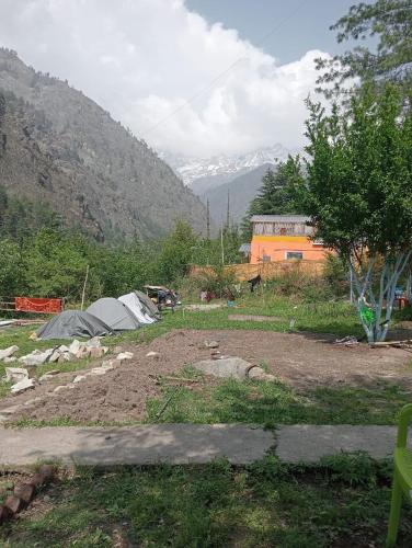 a group of tents in a field with mountains at Yeti Stay Kasol in Jhungi