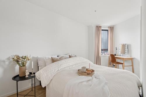 a white bedroom with a white bed and a table at Seaside apartment in Tromsø