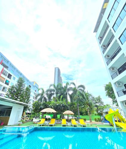 a swimming pool with yellow chairs and a slide at The Regizt Jomtien Pattaya in Jomtien Beach
