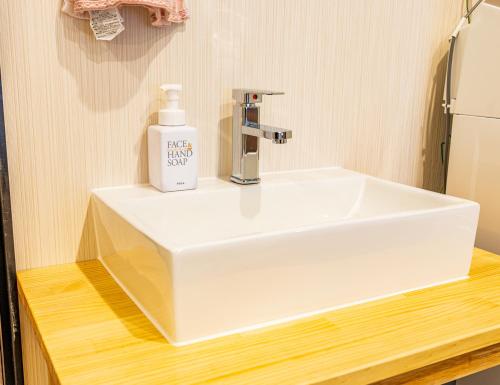 a white bathroom sink with a soap bottle on it at Lax奈良 奈良観光に便利な和モダン古民家 最大12名 グループや家族旅行に最適 in Nara