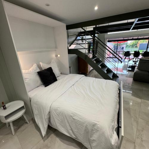 a bedroom with a white bed and a staircase at Maison au bord de la plage - Bottaï in Port-de-Bouc