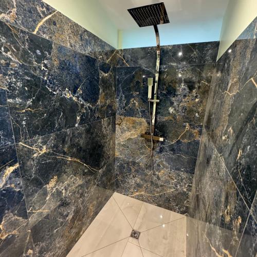 a bathroom with a black marble wall at Maison au bord de la plage - Bottaï in Port-de-Bouc