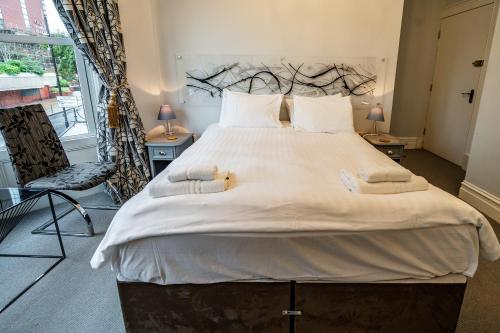 a large bed with white sheets and towels on it at The Camberley in Harrogate