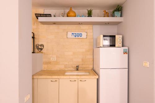 a small kitchen with a sink and a refrigerator at בקתות ילוז של רשת לב הגולן - 6 צימרים מקסימים עם בריכה משותפת ליד הכנרת in Yavneʼel