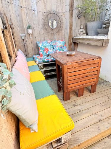 un banc sur une terrasse avec une table et des oreillers dans l'établissement LE PATIO de PROVENCE en AVIGNON - hypercentre, clim, WIFI, calme, à Avignon