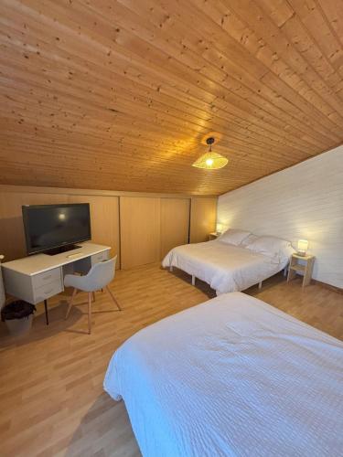 une chambre avec deux lits, un bureau et une télévision dans l'établissement Le Chai du Père Igord - 20 personnes, à Monestier