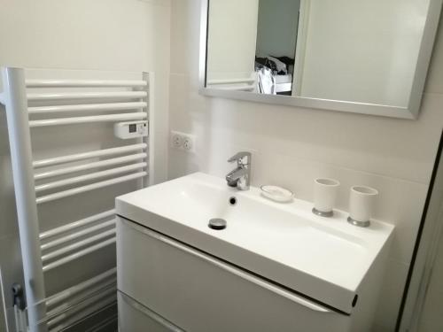 une salle de bain blanche avec un lavabo et un miroir dans l'établissement Vue mer panoramique et plage à 50 m, à Bénodet