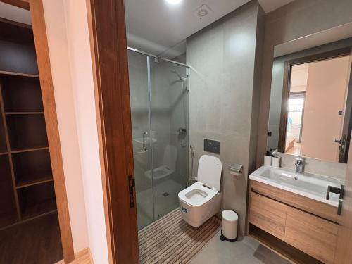 Un baño con inodoro, ducha y lavabo. en Bain de soleil à Dar Bouazza, en Dar Bouazza