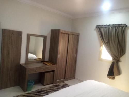 a bedroom with a mirror and a wooden dresser at سمو الخير in Haradh Camp