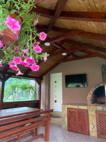 a room with a bench and a fireplace with pink flowers at Apartmani Pavlović in Rogačica