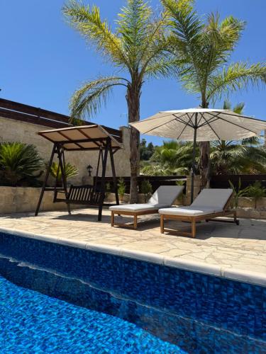 two chairs and umbrellas next to a swimming pool at Stunning Traditional Stone Villa - Kallepia in Kallepia