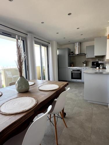 une cuisine et une salle à manger avec une table et des chaises en bois dans l'établissement Lea's cozy nest with a sea-mountain view, à Saint-Laurent-du-Var
