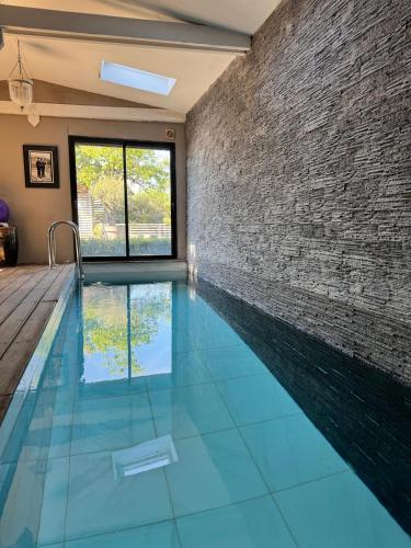 - une piscine avec un mur en briques et du carrelage bleu dans l'établissement Maison architecte pays d Auge, à Préaux