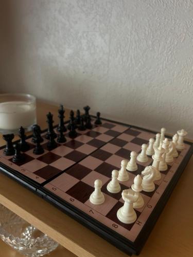 a chess board on a table with a glass of milk at Vieno kambario butas in Palanga