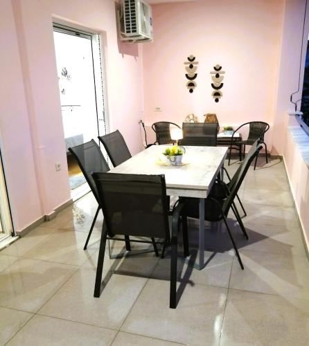 a dining room with a white table and black chairs at Aelio Deluxe Apartment Akrata in Paralía Akrátas