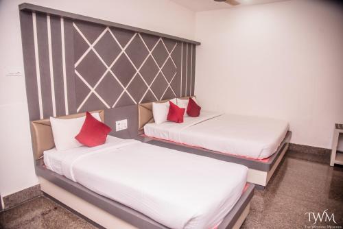 two beds with red pillows in a room at Hotel La Vista Inn in Tinsukia