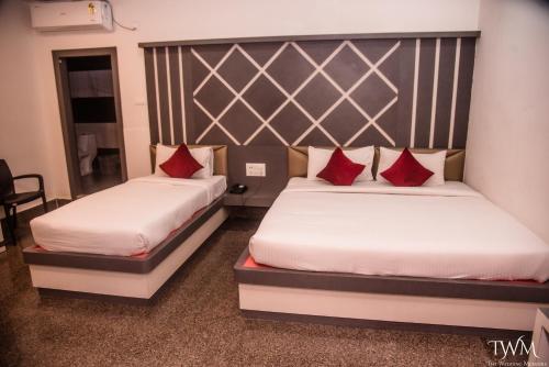 two beds in a hotel room with red pillows at Hotel La Vista Inn in Tinsukia