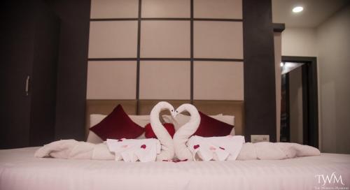 two white swans making a heart shape on a bed at Hotel La Vista Inn in Tinsukia