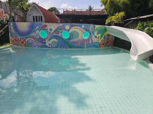 a water slide in a pool with a mosaic wall at Cove Wong Village in Tumbak Bayuh