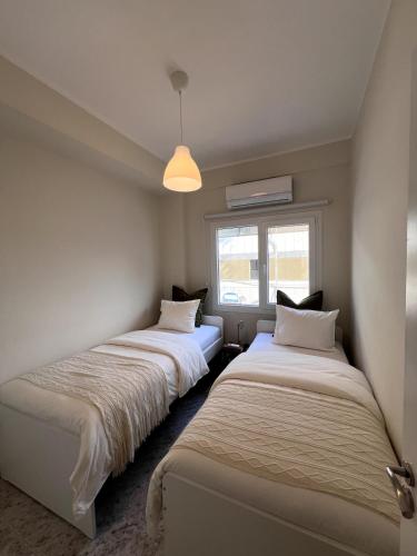 Dos camas en una habitación con ventana. en Casi-Homes, en Lárnaca