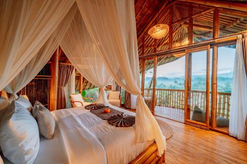 a bedroom with a bed in a room with windows at Jiva Bali - Green Dream in Selat
