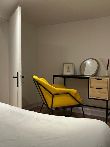 - une chambre avec une chaise jaune et un bureau dans l'établissement Cozy garden house, à Châteaubriant