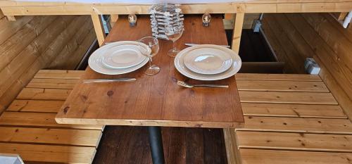 a wooden table with plates and wine glasses on it at L escale enchantée in Gembloux
