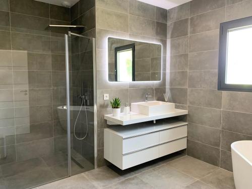 un bagno con lavandino, doccia e specchio di Luxurious Architect-Designed Villa with Pool a Belin-Beliet