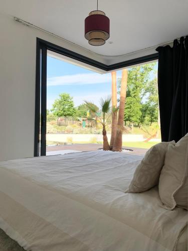 une chambre avec un grand lit avec une grande fenêtre dans l'établissement Luxurious Architect-Designed Villa with Pool, à Belin-Beliet