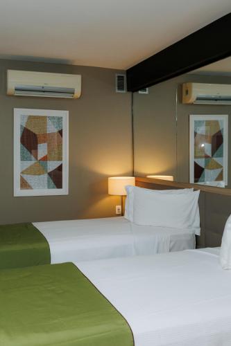 a hotel room with two beds and a lamp at eSuites Savassi Toscanini in Belo Horizonte