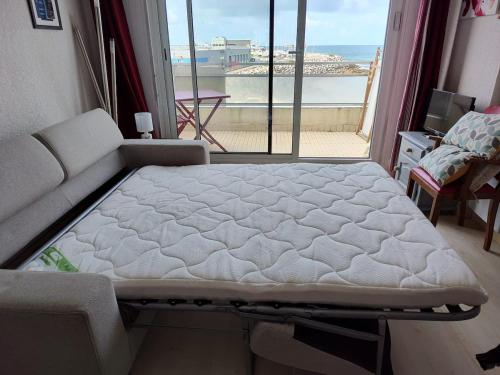 un lit dans une chambre avec une grande fenêtre dans l'établissement Studio vue mer - La Turballe, à La Turballe