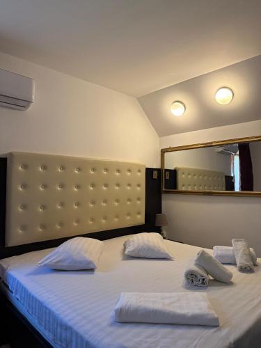 a bedroom with a bed with two pillows and a mirror at Pensiunea El Plazza in Băile Herculane